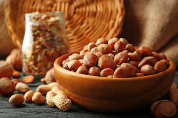 Hazelnuts, walnuts, peanuts in the bowl and glass jar on the table
