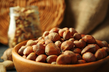 Hazelnuts, walnuts, peanuts in the bowl and glass jar on the table, close-up