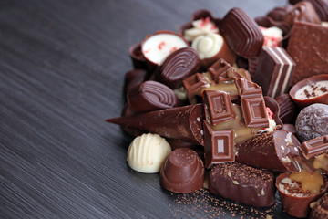 Assortment of tasty chocolate candies on wooden table background