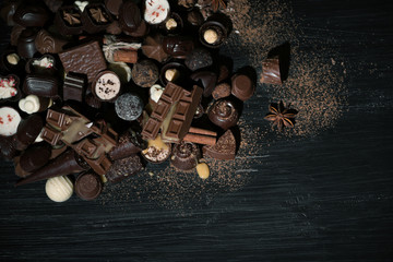 Assortment of tasty chocolate candies and cinnamon on wooden table background