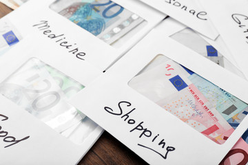 Distribution of money, financial planning, euro in envelopes, on wooden table background