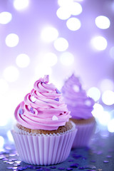 Two cupcakes on a glitter background, close up