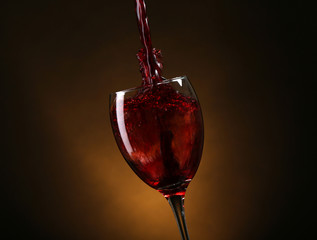 Wine pouring in glass on brown background