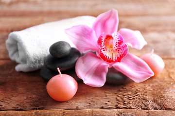 Spa stones with pink orchid, candle and towel on wooden background