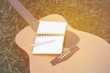 Concept song composer.Notebook and pen on the guitar.Process in vintage color tone