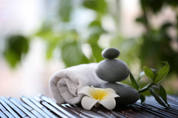 Spa stones with towel and tropical flower on blurred background