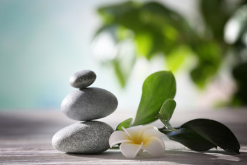 Fototapeta na wymiar Spa stones with tropical flower on blurred background