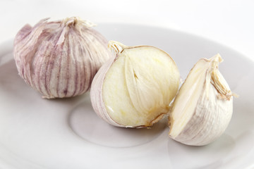 Single clove garlics on white dish , whole and halves