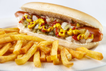 Hot dog with french fries closeup on white plate..