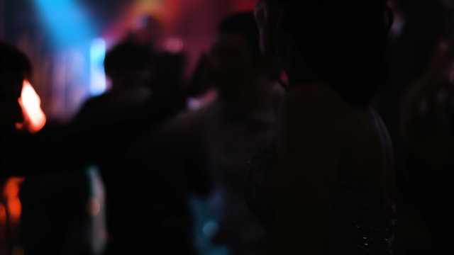 Young handsome lady worn on fancy dress is dancing at nightclub  strobe and colorful lights on the background. 