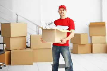 Man holding carton box full of office stationery in the room, close up