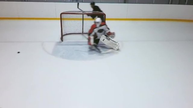 High angle view of hockey player skating towards net and trying to score goal 