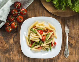 Pasta salad with  tomatoes on the kitchen table, top view