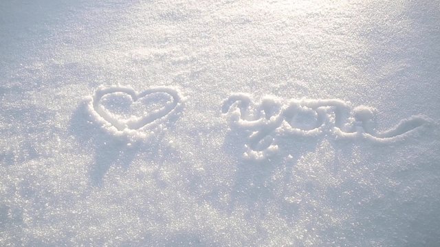 Sunny love you sign with heart symbol handwritten on fresh snow background. Left to right dolly slider move.