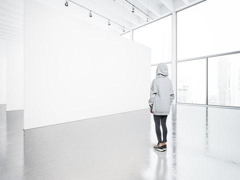 Photo of girl in  contemporary gallery looking at the blank canvas. 