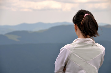 Fototapeta premium Girl on the top of a mountain and looks into distance