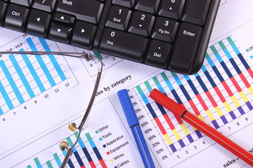 Pen, glasses and computer keyboard on financial graph, business concept