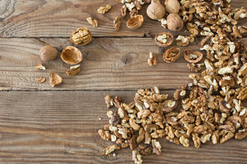 Walnut kernels and whole walnuts on rustic old wooden table