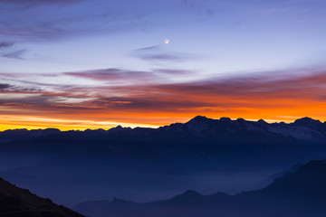 Mountain silhouette and stunning sky with moon at sunset