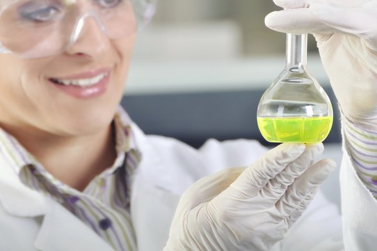 Attractive young PhD student scientist observing the green indicator color shift after the solution destillation in chemical laboratory