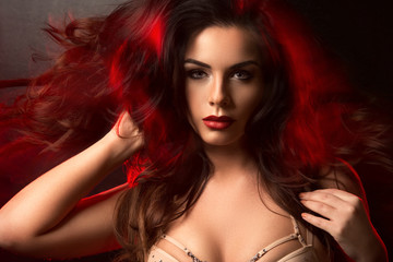 Hot brunette woman in red light on hair
