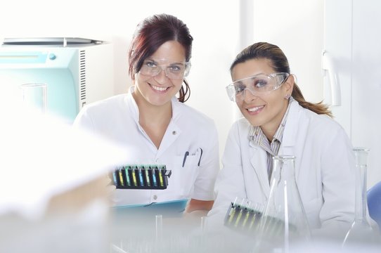 Attractive young PhD students scientists  observing the blue, yellow and green indicator color shift after the solution destillation in chemical laboratory 