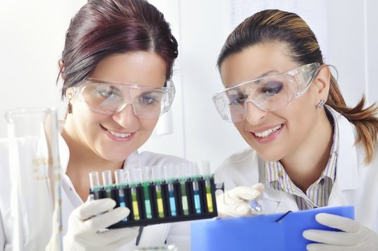 Attractive young PhD students scientists  observing the blue, yellow and green indicator color shift after the solution destillation in chemical laboratory 