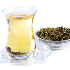 Glass cup of brewed green tea, close-up, on a gleam, isolated on