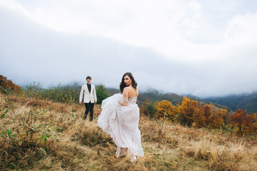 happy newly married couple posing in the mountains