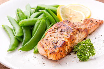 Grilled salmon with lemon, green bean and herb, on white dish. Dinner concept