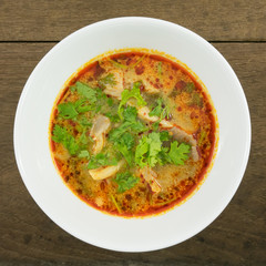 The tasty spicy pork tom yum soup (hot and sour soup) in white ceramic bowl, homemade Thai food.