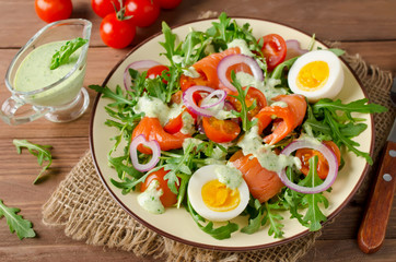 Obraz na płótnie Canvas Smoked salmon salad with arugula, tomatoes, eggs and red onion