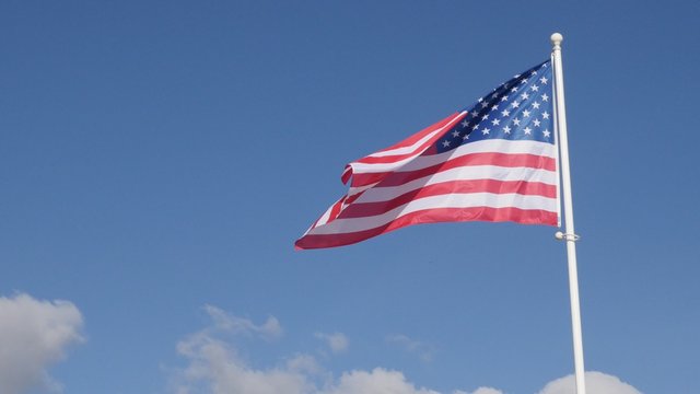 United States of America flag in front of blue sky floating on wind 4K 2160p UltraHD footage - American flag on sunny day in front of sky waving 4K 3840X2160 30fps UHD video