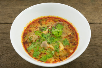 The tasty spicy pork tom yum soup (hot and sour soup) in white ceramic bowl, homemade Thai food.