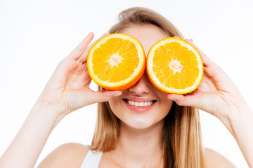 Funny cheerful woman holding two halves of orange agains eyes