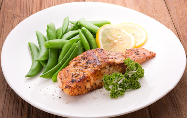 Grilled salmon with lemon, green bean and herb, on white dish. Dinner concept
