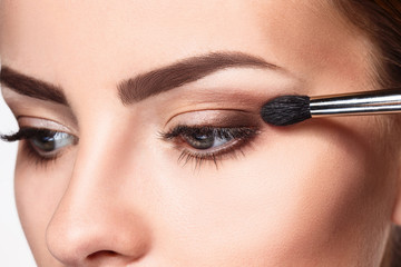 Beautiful female eyes with bright blue make-up and brush