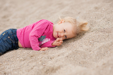child is lying on the beach