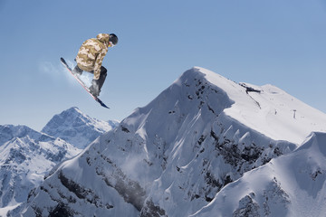 Flying snowboarder on mountains. Extreme sport.