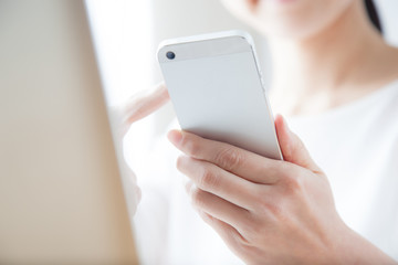 携帯電話でインターネットをする女性　ラップトップ　ノートパソコン