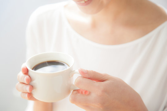 コーヒーを飲む女性　笑顔　窓際