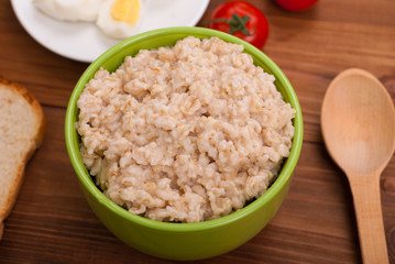 Oatmeal in a bowl on the wooden table.