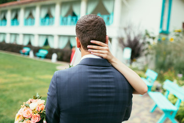 bride with wedding bouquet hug groom on neck with her hand on we