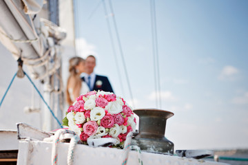 Wedding bridal bouquet with pink and white roses on a yacht