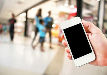 Female hand holding mobile smart phone on Supermarket blur background, business concept