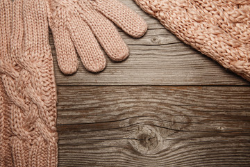 Pink knitted warm gloves, hat and sharf on old texture backgroun