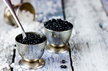 Fototapeta na wymiar Black caviar in small round metal tin on ice. Selective focus