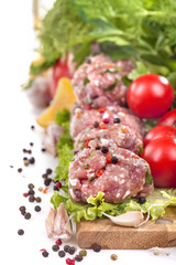 Fresh meatballs with various vegetables on a white background