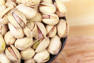 Closeup of a bowl of pistachios on wooden table