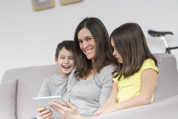 Smiling mother and children using tablet